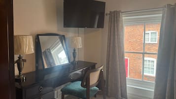 Una habitación con escritorio, silla y televisión instalada en la pared.