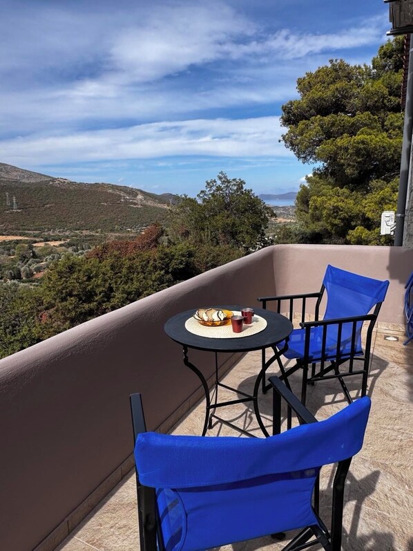 Un balcón con mesa y sillas, un plato de comida y vistas del paisaje.