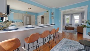 A modern kitchen with a central island, bar stools, and a dining area with a table and chairs. - Beautiful Modern Beach House In Old Orchard Beach! w/ optional In-Law Apartment! (Old Orchard Beach)