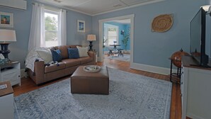 A living room with a brown sofa, a patterned rug, and a dining area with a table and chairs. - Beautiful Modern Beach House In Old Orchard Beach! w/ optional In-Law Apartment! (Old Orchard Beach)