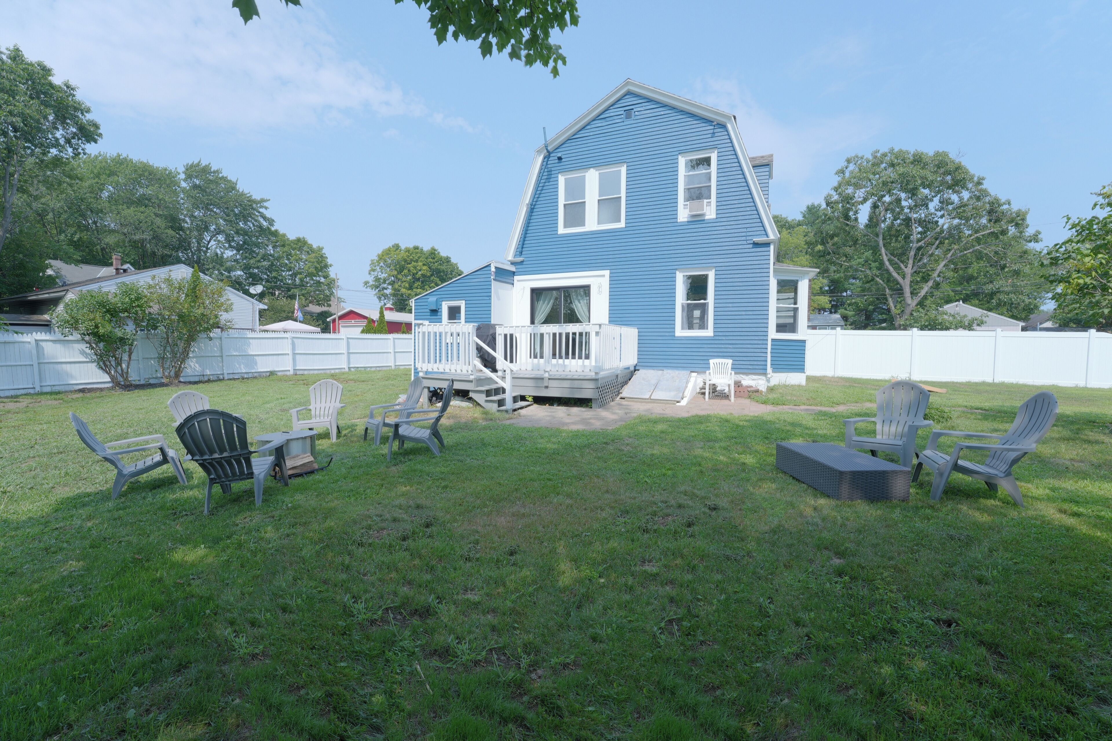 A blue house with a white porch and a fenced backyard.