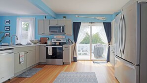 A modern kitchen with white cabinets, a stainless steel refrigerator, a microwave, and an oven. There is a sign that reads "SEASIDE" on the wall. - Beautiful Modern Beach House In Old Orchard Beach! w/ optional In-Law Apartment! (Old Orchard Beach)