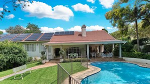 A house with a swimming pool, solar panels, and a covered patio.