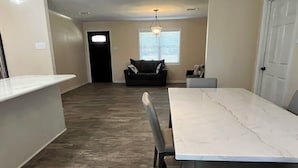Een ruime woonkamer met een marmeren eettafel, een bank en een lange houten zitting.