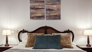 A neatly made bed with a wooden headboard, two bedside lamps, and a textured blanket.