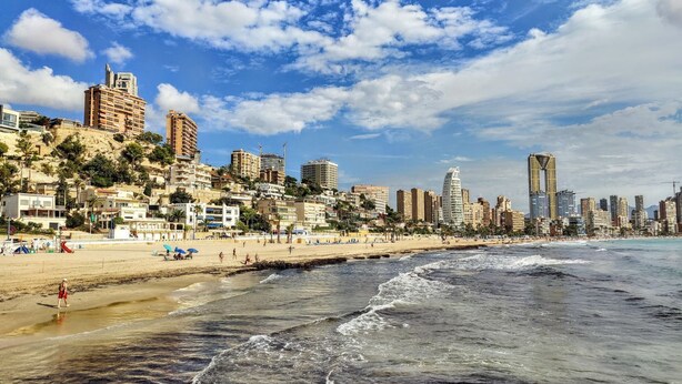 A coastal cityscape with a beach, high-rise buildings, and a clear sky.