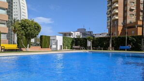 A swimming pool with a bench and a tree in the background.
