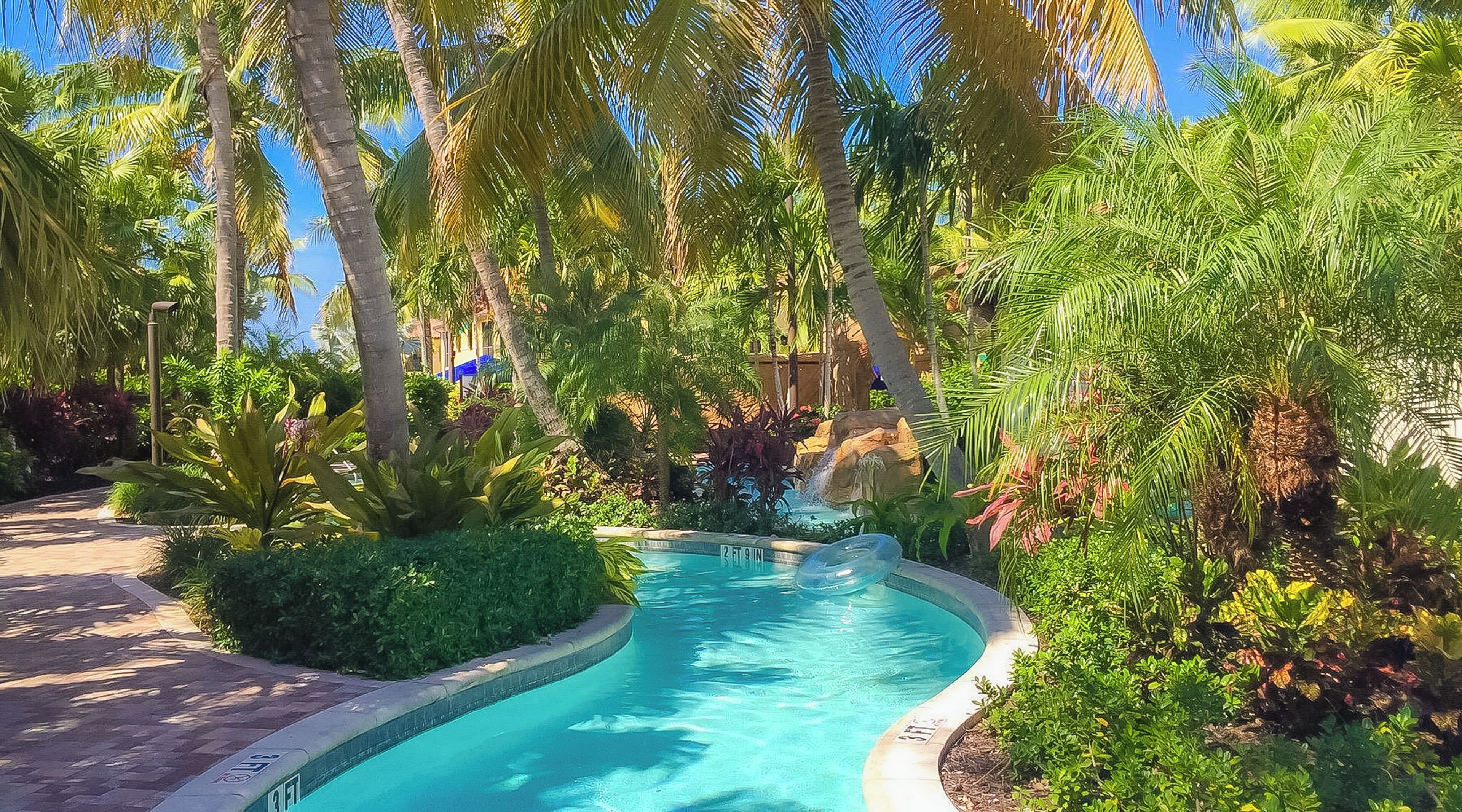 Piscina rodeada por vegetação exuberante e palmeiras.