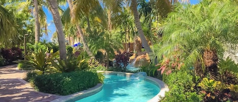 Piscina rodeada por vegetação exuberante e palmeiras.