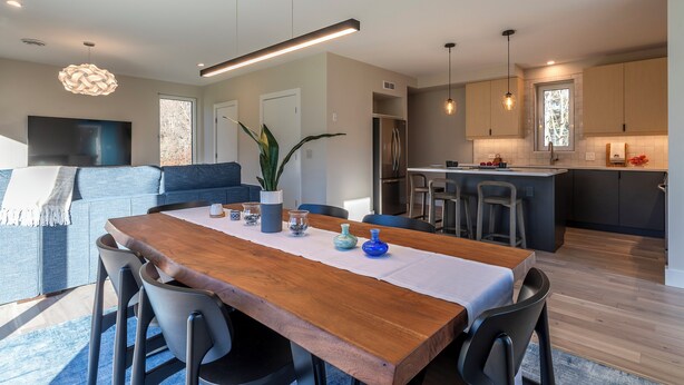 Una cocina moderna con una isla central, electrodomésticos integrados y un comedor con mesa y sillas de madera.