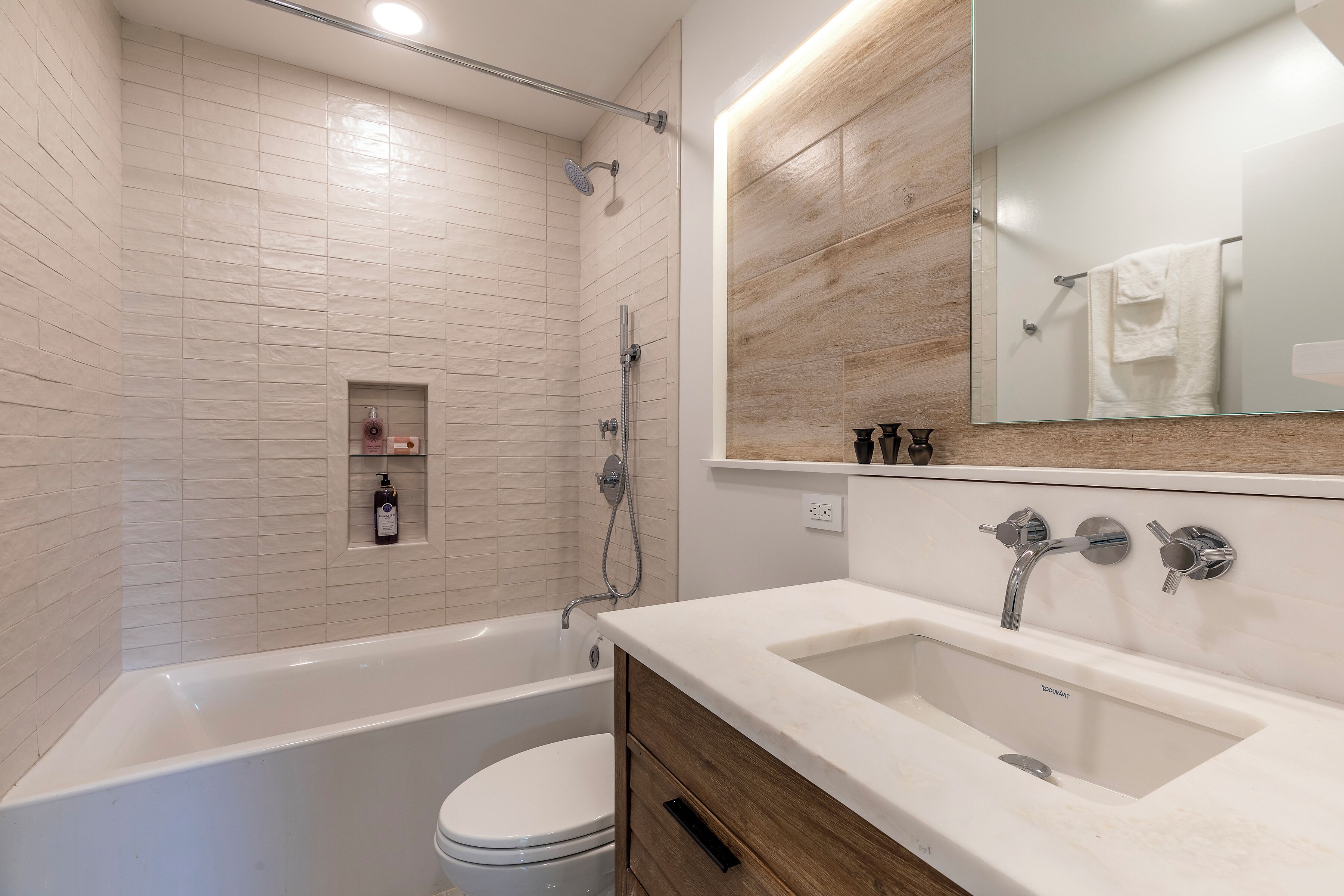A modern bathroom with a bathtub, toilet, and vanity with a sink.