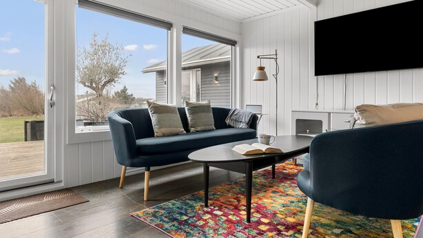 Ein modernes Wohnzimmer mit einem dunkelblauen Sofa, einem runden Couchtisch und einem farbenfrohen Teppich.