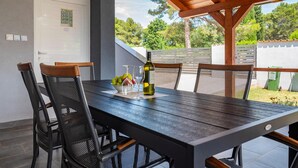 A wooden dining table with chairs, a bottle of wine, and a bowl of fruit. - 3 bedroom beautiful apartment in Peroj (Peroj)