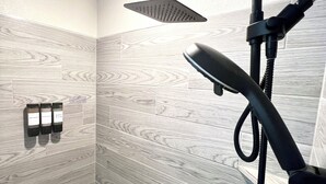 Une salle de bain équipée d’une douche, d’un pommeau de douche amovible et d’un luminaire fixé au mur.