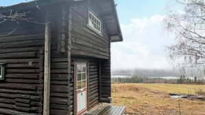 Een rustieke blokhut met een houten deur en raam, gelegen in een natuurlijke omgeving.