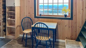 Een gezellige kamer met houten details, een raam met uitzicht, twee blauwe stoelen en een klein tafeltje.