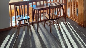 A loft-style room with a wooden dining table and chairs, large windows, and a sloped ceiling. - Cozy lakefront cabin on Big Beaver Lake (Big Lake)