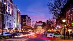 A street view at dusk with buildings, parked cars, and a clear sky. - Pet-Friendly Family Home w/ Yard (Gainesville)