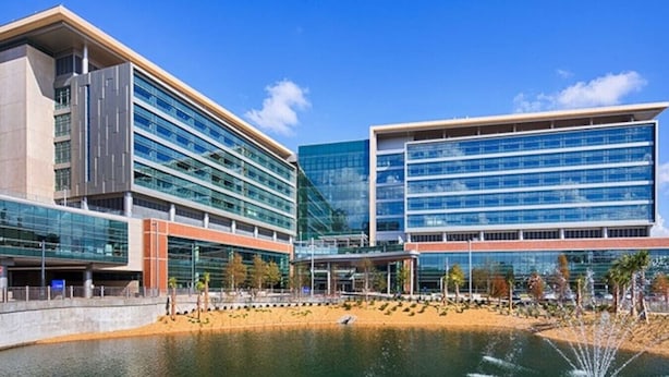 A modern building with multiple floors, large windows, and a water feature in the foreground. - Pet-Friendly Family Home w/ Yard (Gainesville)
