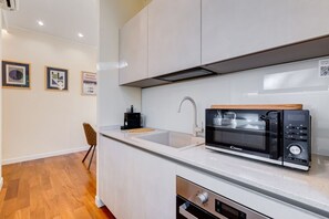 Una cocina moderna con microondas, lavamanos y armario.