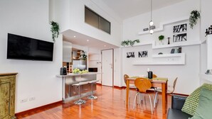 A modern living space with a kitchen, dining area, and a TV mounted on the wall.