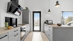 A modern kitchen with a central island, a built-in oven, and a large window.