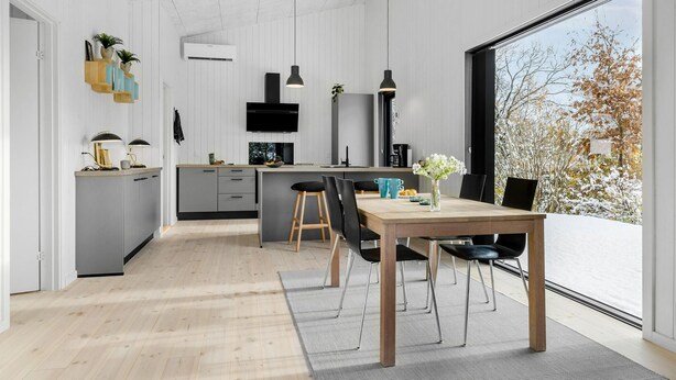 A modern kitchen with a central island, pendant lighting, and a view of trees through a large window.
