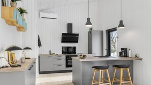 A modern kitchen with a central island, bar stools, a built-in oven, and pendant lighting.