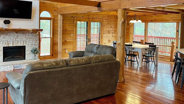 A spacious living room with a stone fireplace, wooden floors, and a high ceiling with exposed beams. - Secluded lakeside retreat with lake view and hot tub. Close to Mammoth Cave.  (Cub Run)