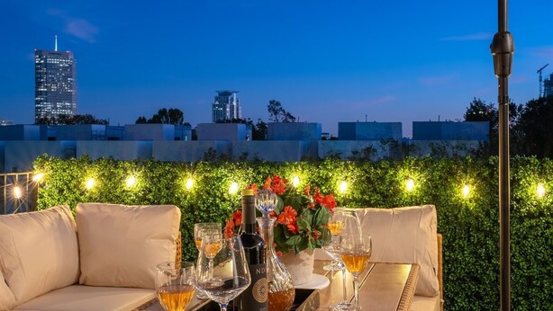 An outdoor dining area with a table set for two, a wicker chair, and an umbrella. - Premium House for 10 w/ Rooftop Deck in Rice Mil (HOUSTON)