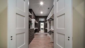 A modern hallway with white doors, a wooden floor, and a mirror on the left wall. - Premium House for 10 w/ Rooftop Deck in Rice Mil (HOUSTON)