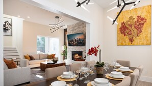 A modern living room with a dining area set for a meal. - Premium House for 10 w/ Rooftop Deck in Rice Mil (HOUSTON)