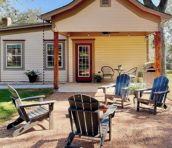 A house with a covered patio area featuring outdoor furniture and a fire pit. - The Lazey Dazey Cottage, Dating back to 1884 in Hico, Texas (Hico)
