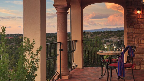 Une terrasse avec une table et des chaises, une vue sur la campagne et un mur en pierre.