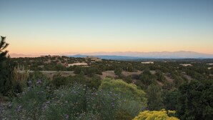 Un paysage avec quelques bâtiments dispersés, des montagnes à l’horizon et une végétation variée.
