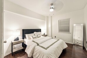 Relax in this serene bedroom with a large bed, nightstand, and ceiling light fixture.