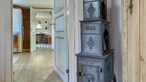 A hallway with a vintage metal safe, wooden flooring, and a door leading to a room with a bed and a table.