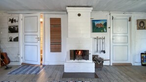 A room with a fireplace, wooden floors, and white walls.
