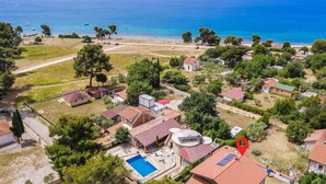 An aerial view of a coastal residential area with houses, a swimming pool, and a beach. - Cozy apartment in Peroj with WiFi (Peroj)