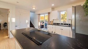 A modern kitchen with a large island, white cabinetry, and a built-in oven. - Bryce Zion Vacation (Kane County)