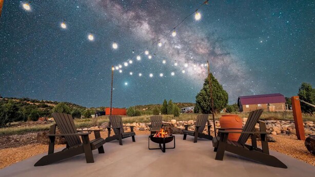 An outdoor seating area with Adirondack chairs and a fire pit, under a starry sky. - Bryce Zion Vacation (Kane County)