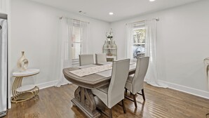 A dining area with a round table, six chairs, and a small side table with a vase. - Cozy Decatur Home with Indoor Fireplace & Firepit (Decatur)