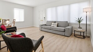 Una sala de estar moderna con un sofá gris, una mesa de centro redonda y una lámpara de pie.