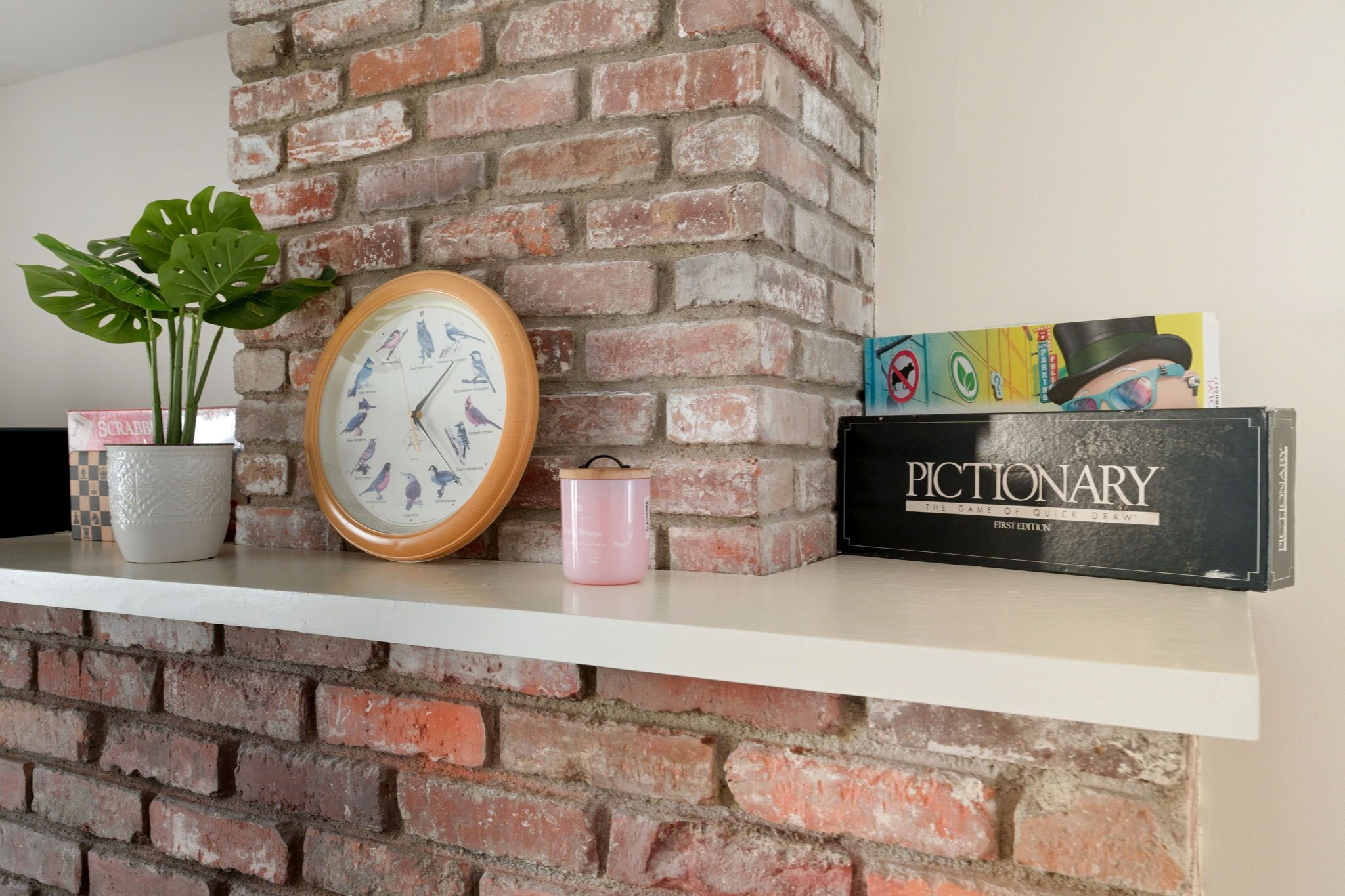 A shelf with a clock, a plant, a mug, and a game box.