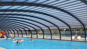 Une piscine intérieure dotée d’un toit abrité, d’une eau claire et d’un toboggan pour les enfants.