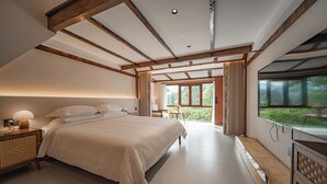A bedroom with a large bed, wooden beams, a bedside table with a lamp, and a view of greenery through a window. - ZhangJiaJieFuXiErYi (Zhangjiajie)