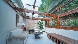 A cozy outdoor seating area with a sofa, a round table, and a wooden bench. A brick fireplace and a potted plant are also visible. - ZhangJiaJieFuXiErYi (Zhangjiajie)