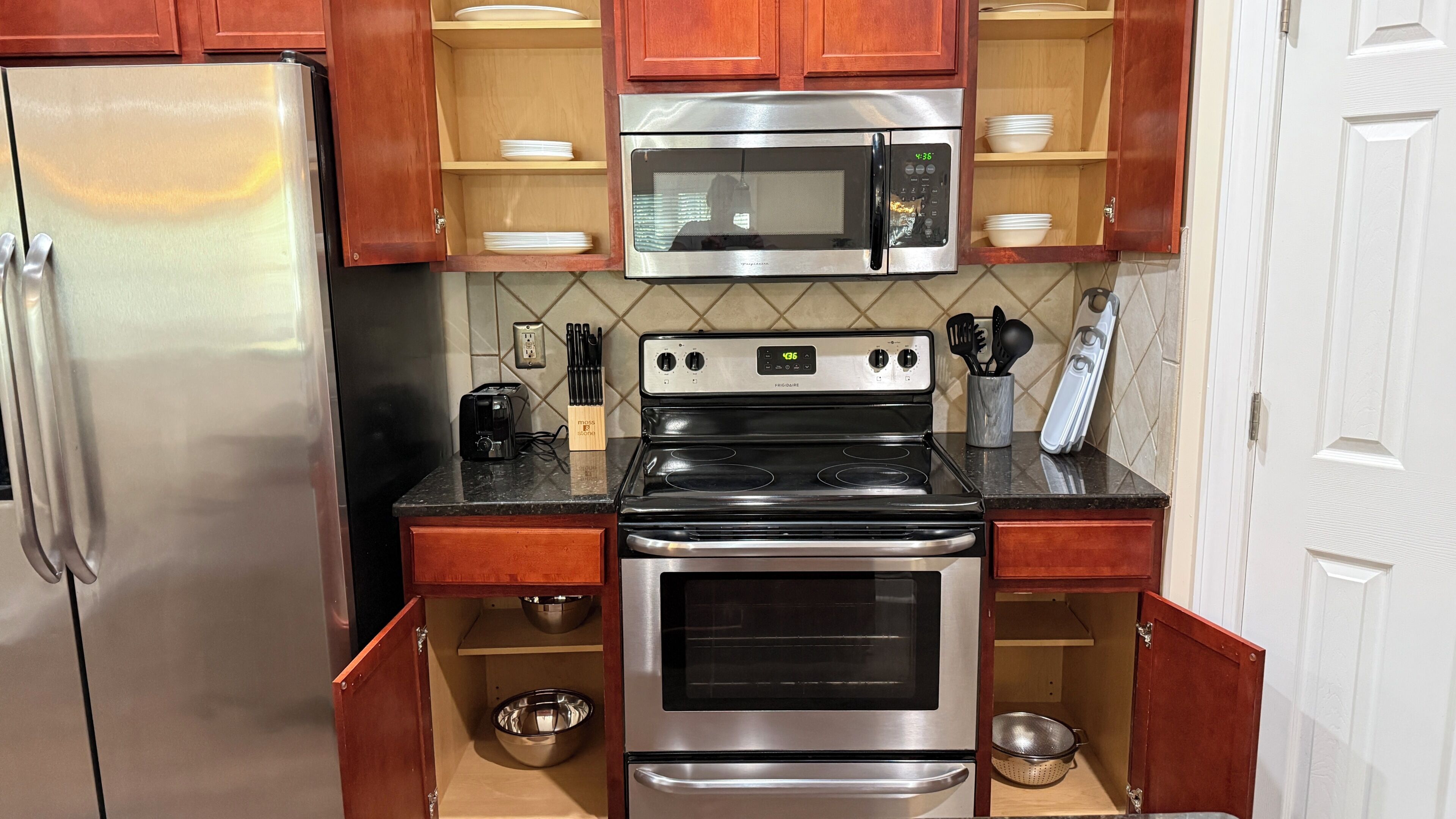 A compact kitchen with a refrigerator, microwave, stove, and oven.