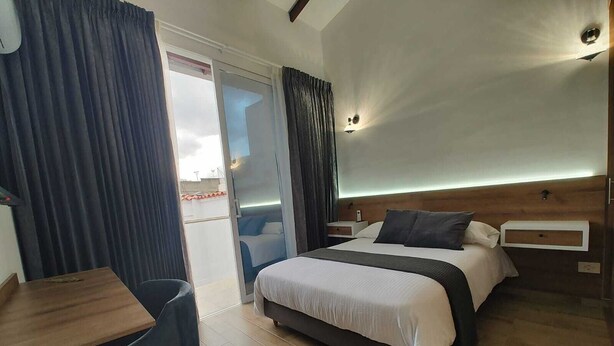 A hotel room with a bed, bedside tables, a desk, and a chair. - Valymar Inn (Cali)