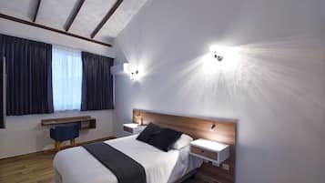 Una moderna camera d'albergo con un ampio letto, comodini, una scrivania e una sedia.